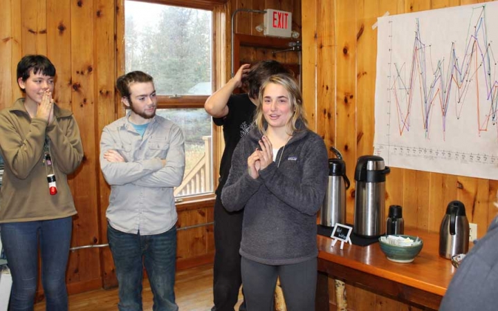 A person speaks to a group of people in front of a chart during the family seminar of an outward bound intercept course.